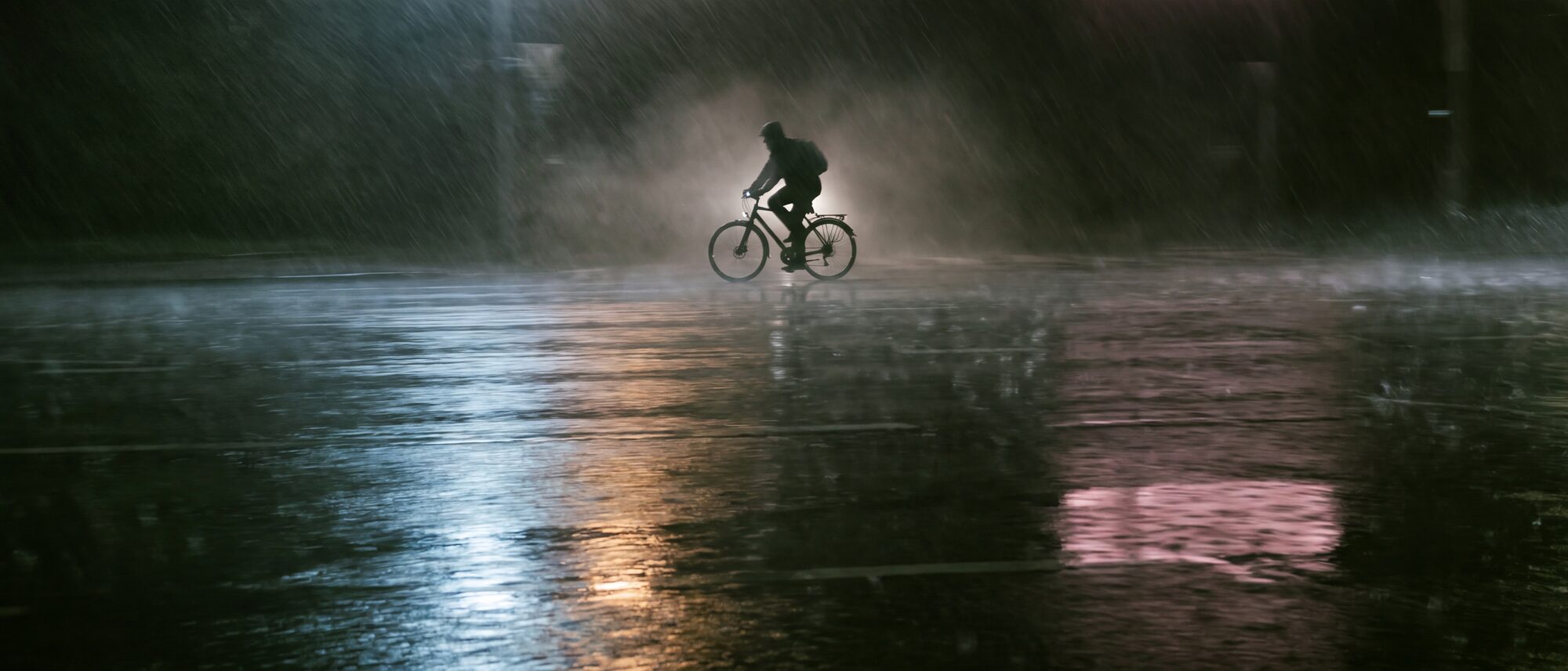 Nat asfalt in de regen met lichtreflecties en een fiets in tegenlicht